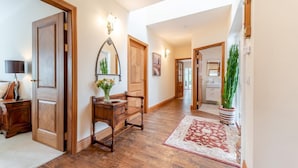 Ein Flur mit Holzboden, einer Bank, einer Blumenvase und einem Spiegel an der Wand.
