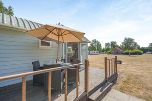A covered outdoor dining area with a table, chairs, and an umbrella.