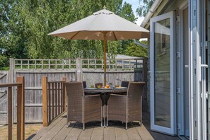 An outdoor patio with a table and chairs, a large umbrella, and a wooden fence. - 1 Bed in Banham (oc-b1900) (Banham)