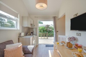 A compact kitchen with a dining area, a sofa, and a TV.