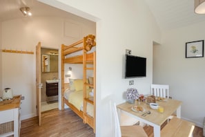 Ein Zimmer mit Etagenbett, Schreibtisch mit Frühstücksangeboten, Fernseher und einem Badezimmer mit Spiegel.