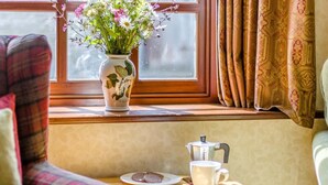 A cozy seating area with a window, a floral vase, a coffee pot, and a cup on a small table. - 4 Bed in Newchurch (oc-bow333) (Newchurch)