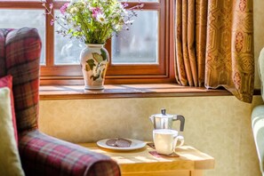 A cozy seating area with a window, a floral vase, a coffee pot, and a cup on a small table. - 4 Bed in Newchurch (oc-bow333) (Newchurch)