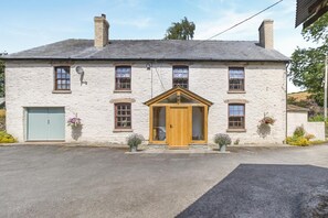 A two-story stone building with a central wooden door, multiple windows, and a small porch area. - 4 Bed in Newchurch (oc-bow333) (Newchurch)
