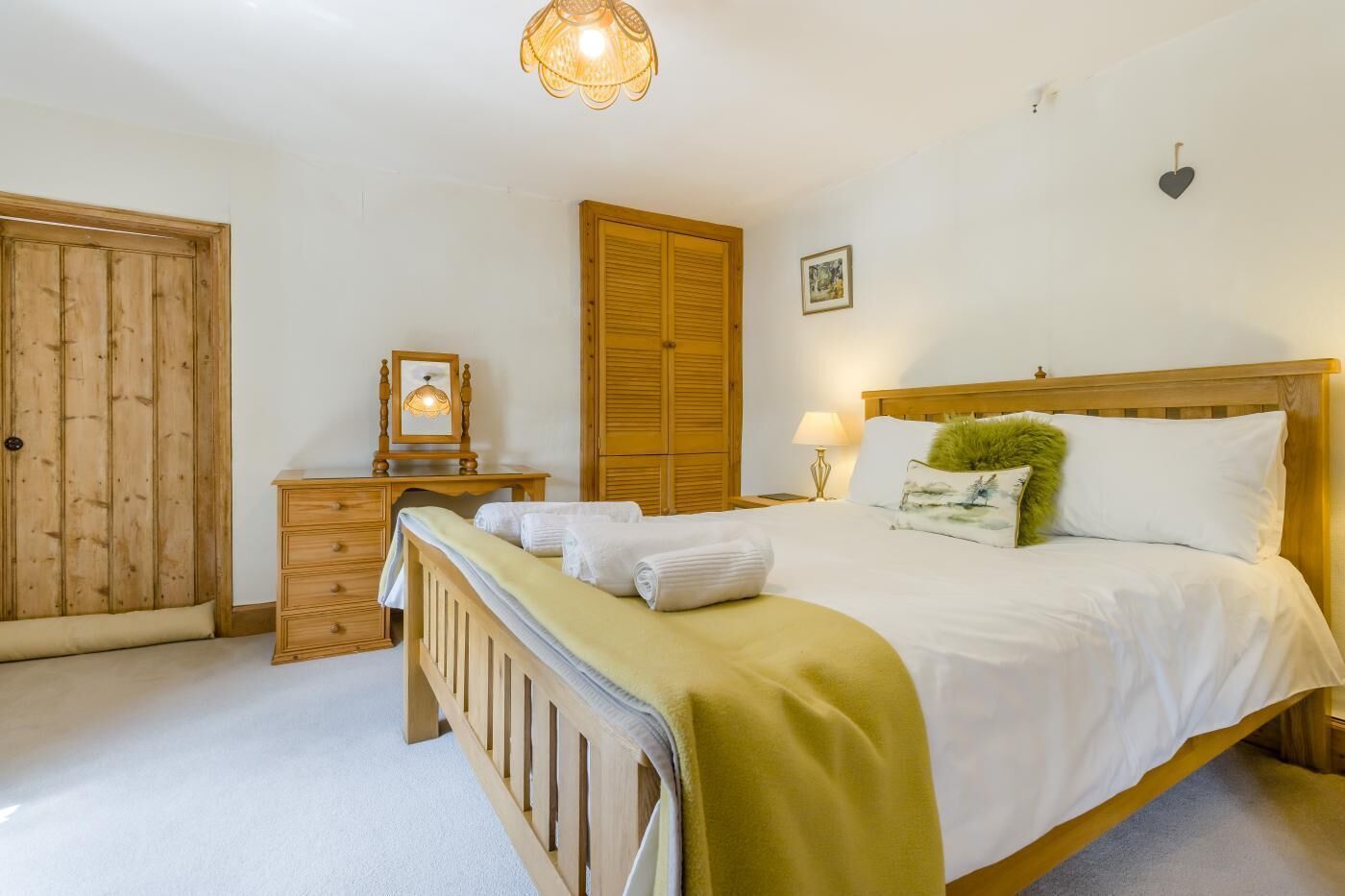 Ein Schlafzimmer mit einem Bett, einem Holzschrank, einem Nachttisch und einer Pendelleuchte.