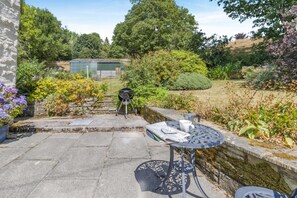 A patio with a grill, a table with a cup and newspaper, and a stone wall. - 4 Bed in Newchurch (oc-bow333) (Newchurch)
