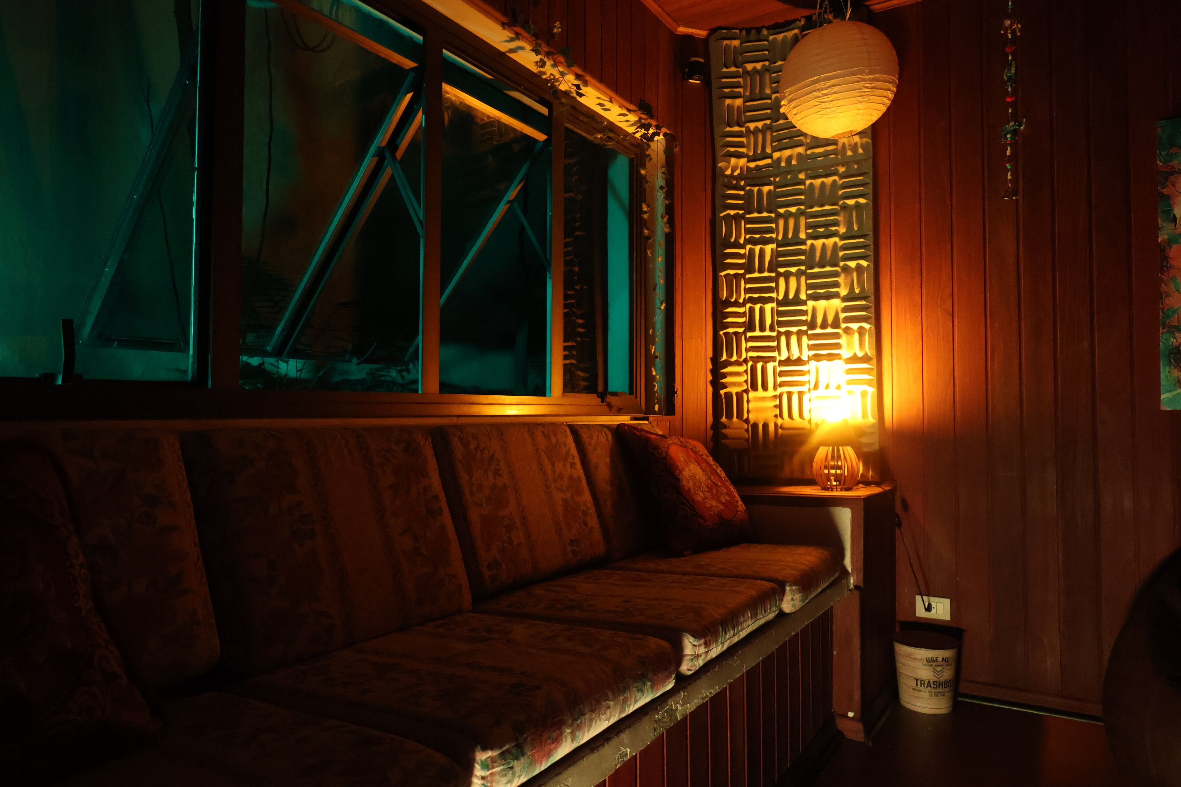 Una habitación tenuemente iluminada con un banco de madera, un papel tapiz decorado y una lámpara colgante.