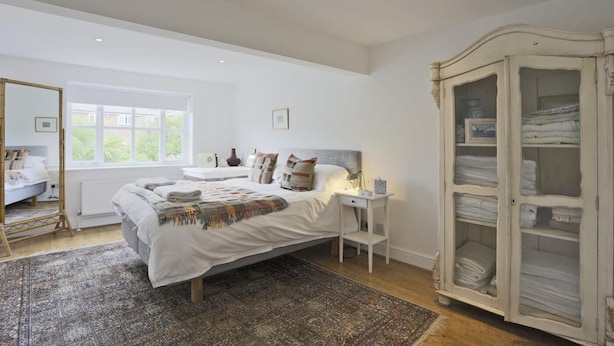 Een slaapkamer met een groot bed, nachtkastje, kledingkast en een raam met uitzicht.