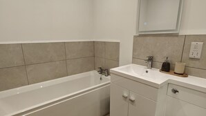 A bathroom with a bathtub, a sink, and a mirror. - 6 Bed in Meidrim (oc-b45396) (Meidrim)