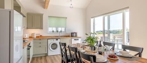 Una cocina moderna con lavadora integrada, suelo de madera y zona de comedor con vistas al exterior.