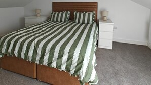 A bedroom with a sloped ceiling, a bed with striped bedding, two bedside tables with lamps, and a ceiling light fixture. - 6 Bed in Meidrim (oc-b45396) (Meidrim)
