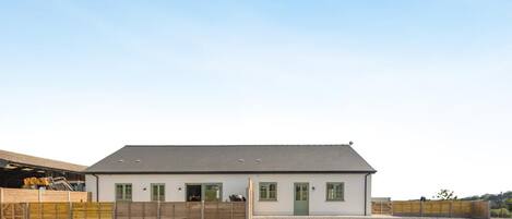 A single-story building with a flat roof, a gravel driveway, and a wooden fence.