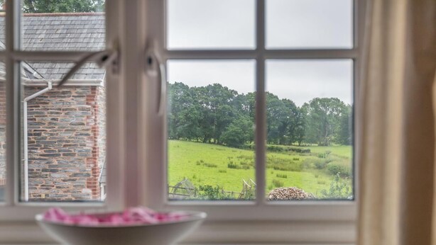 Ein Fenster mit Blick auf ein grünes Feld und eine Ziegelmauer.