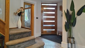 Una escalera conduce a una habitación con una puerta de madera y una ventana con persianas horizontales.