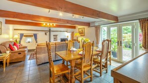 A dining area with a wooden table and chairs, a sofa, and a television in the background. - 2 Bed in Thornton Rust (oc-t45331) (Thornton Rust)