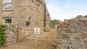 A stone building with a wooden gate, a small window, and a stone wall with a decorative element. - 2 Bed in Thornton Rust (oc-t45331) (Thornton Rust)