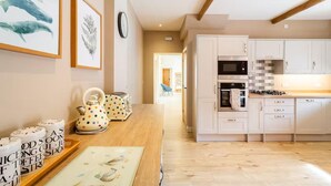 Une cuisine moderne avec des meubles blancs, un plan de travail en bois et une horloge bien visible au mur.