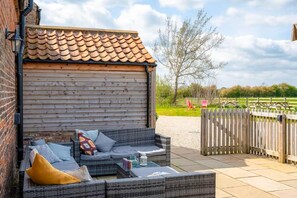 A covered outdoor seating area with wicker furniture, a wooden wall, and a view of a park. - 1 Bed in Marishes (oc-v45394) (Marishes)