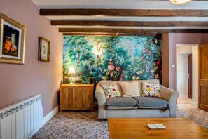 Ein Wohnzimmer mit einer Couch, einem Couchtisch, einer Lampe und einer Wandmalerei.