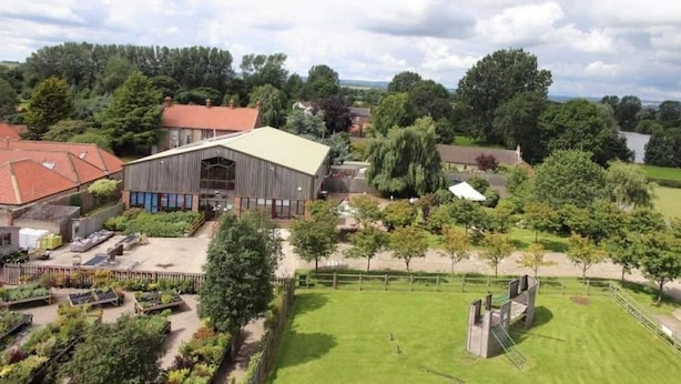 A large building with a flat roof, surrounded by a well-maintained garden and trees.