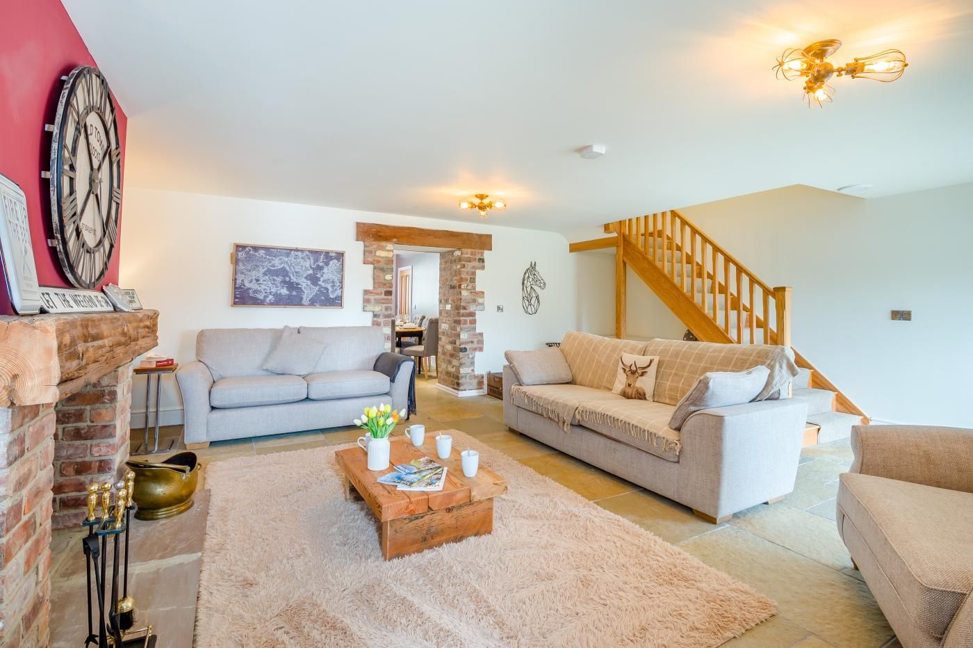 A living room with two sofas, a coffee table, a fireplace, and a staircase.