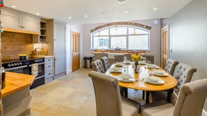 A dining area with a round table set for six, surrounded by upholstered chairs. - 4 Bed in Scorton (oc-t44226) (Scorton)