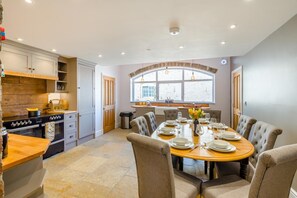 Un coin repas avec une table ronde dressée pour six personnes, entourée de chaises rembourrées.