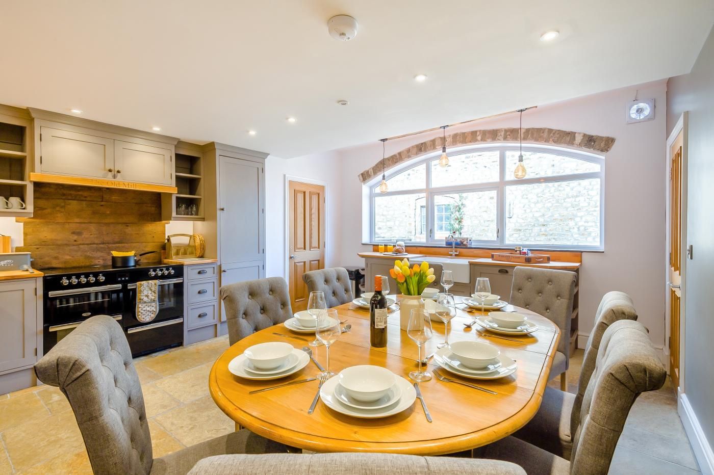 A modern kitchen with a dining table set for six, featuring a built-in oven and ample counter space.