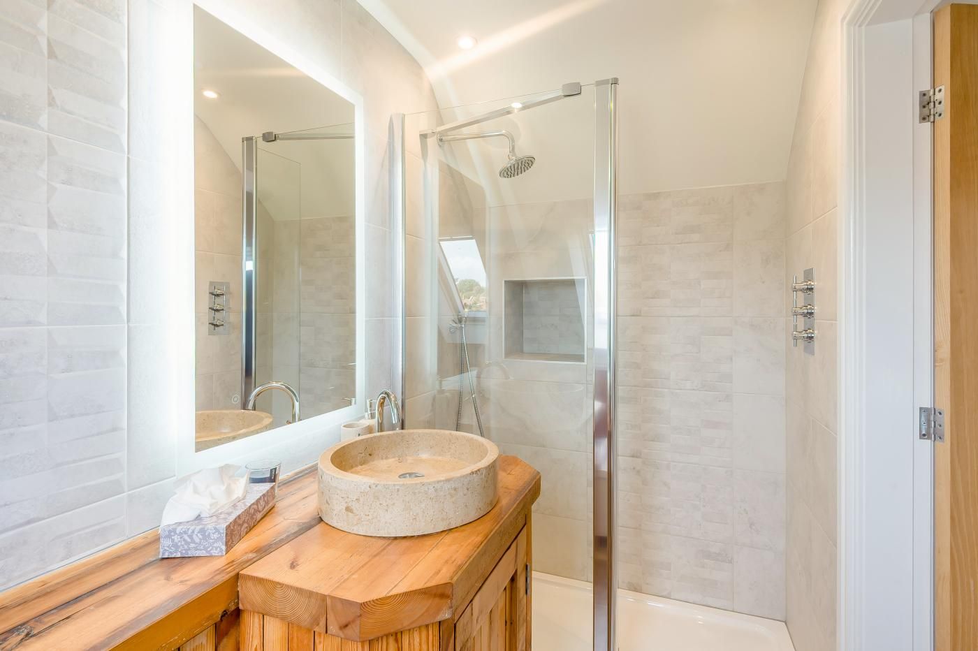 A modern bathroom with a glass shower enclosure, a wooden vanity, and a large mirror.