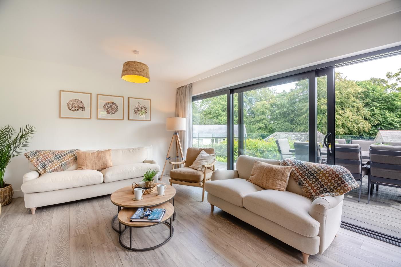 A modern living room with two sofas, a coffee table, and a floor lamp. Large windows provide a view of the outdoors.