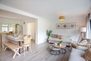 Ein modernes Wohnzimmer mit Sofa, Couchtisch und Essbereich mit Stühlen und einer Bank.