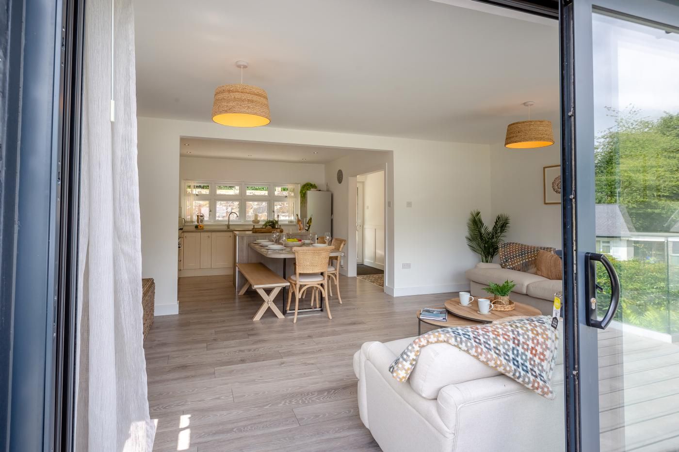 A modern interior with a dining area, a sofa, and a view through a glass door.
