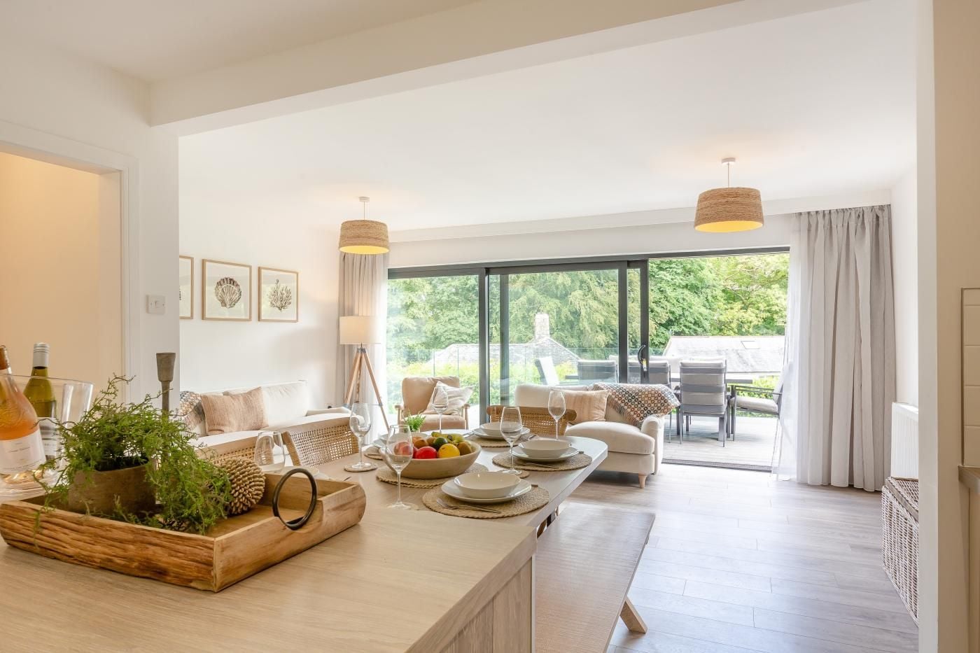 A spacious dining area with a long table set for a meal, surrounded by comfortable seating and large windows offering a view of the outdoors.