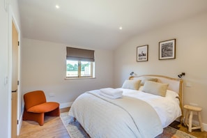 A bedroom with a bed, a chair, a window, and two framed pictures on the wall. - 2 Bed in Bardwell (oc-d44861) (Bardwell)