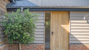 A wooden door with a metal handle, a small tree, and a brick wall. - 2 Bed in Bardwell (oc-d44861) (Bardwell)