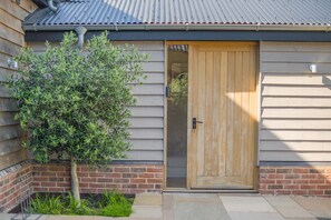 A wooden door with a metal handle, a small tree, and a brick wall. - 2 Bed in Bardwell (oc-d44861) (Bardwell)