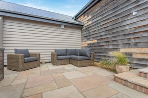 An outdoor patio area with a wicker sofa set and a potted plant. - 1 Bed in Bardwell (oc-l44860) (Bardwell)