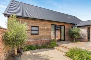 A two-story house with a sloped roof, a brick foundation, and a wooden exterior.