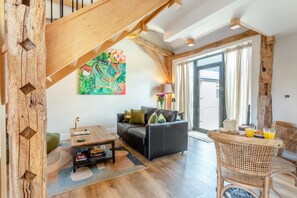 Ein modernes Wohnzimmer mit einer Holztreppe, einer Sofagarnitur, einem Couchtisch und einem Korbstuhl.