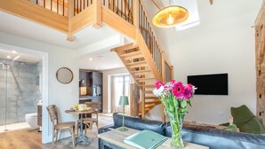 Un salon moderne avec un escalier, un coin repas et une cuisine.