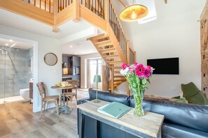 Ein modernes Wohnzimmer mit Treppe, Essbereich und Küche.