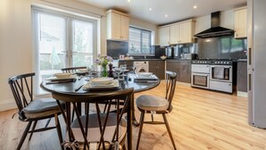 Una cocina moderna con zona de comedor, suelo de madera y ventanas amplias.