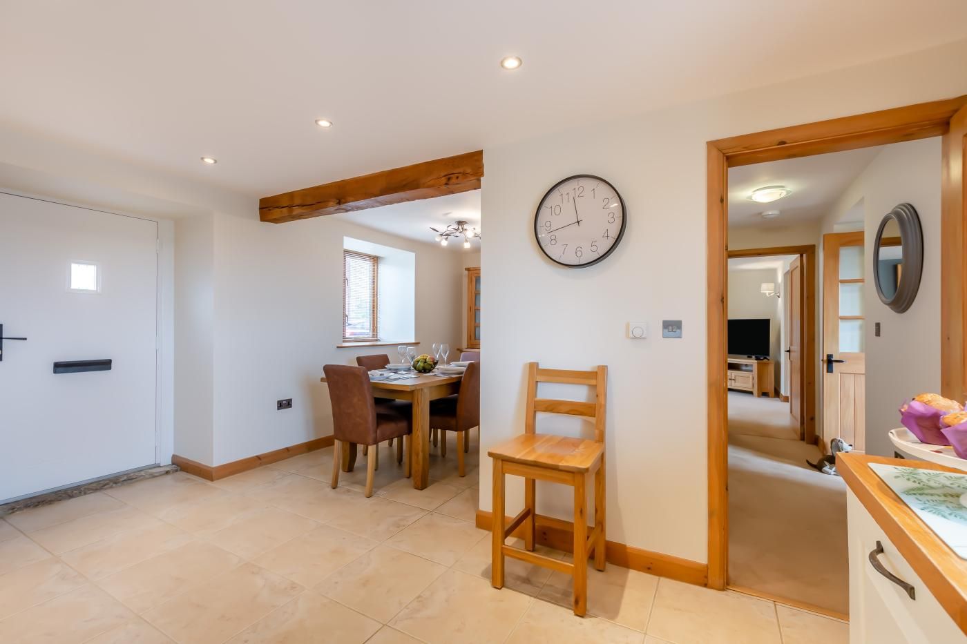 Una habitación amplia con zona de comedor, una silla de madera y un reloj de pared.