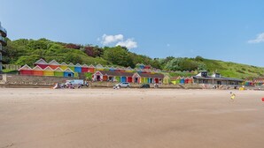 Ein Strand mit bunten Strandkörben und blauem Himmel.