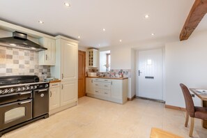 A modern kitchen with a built-in stove, white cabinets, and a dining area with a wooden table and chairs. - 2 Bed in Sawdon (oc-w45349) (Sawdon)
