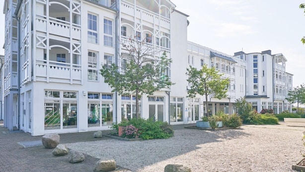 A multi-story hotel with a symmetrical facade, large windows, and a gravel courtyard with trees. - Schone Ferienwohnung mit Wanne und Grossem Balkon in Sellin (Sellin)