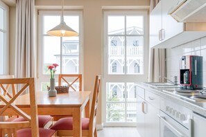 A kitchen with a dining area, large windows, and a view of a building. - Schone Ferienwohnung mit Wanne und Grossem Balkon in Sellin (Sellin)
