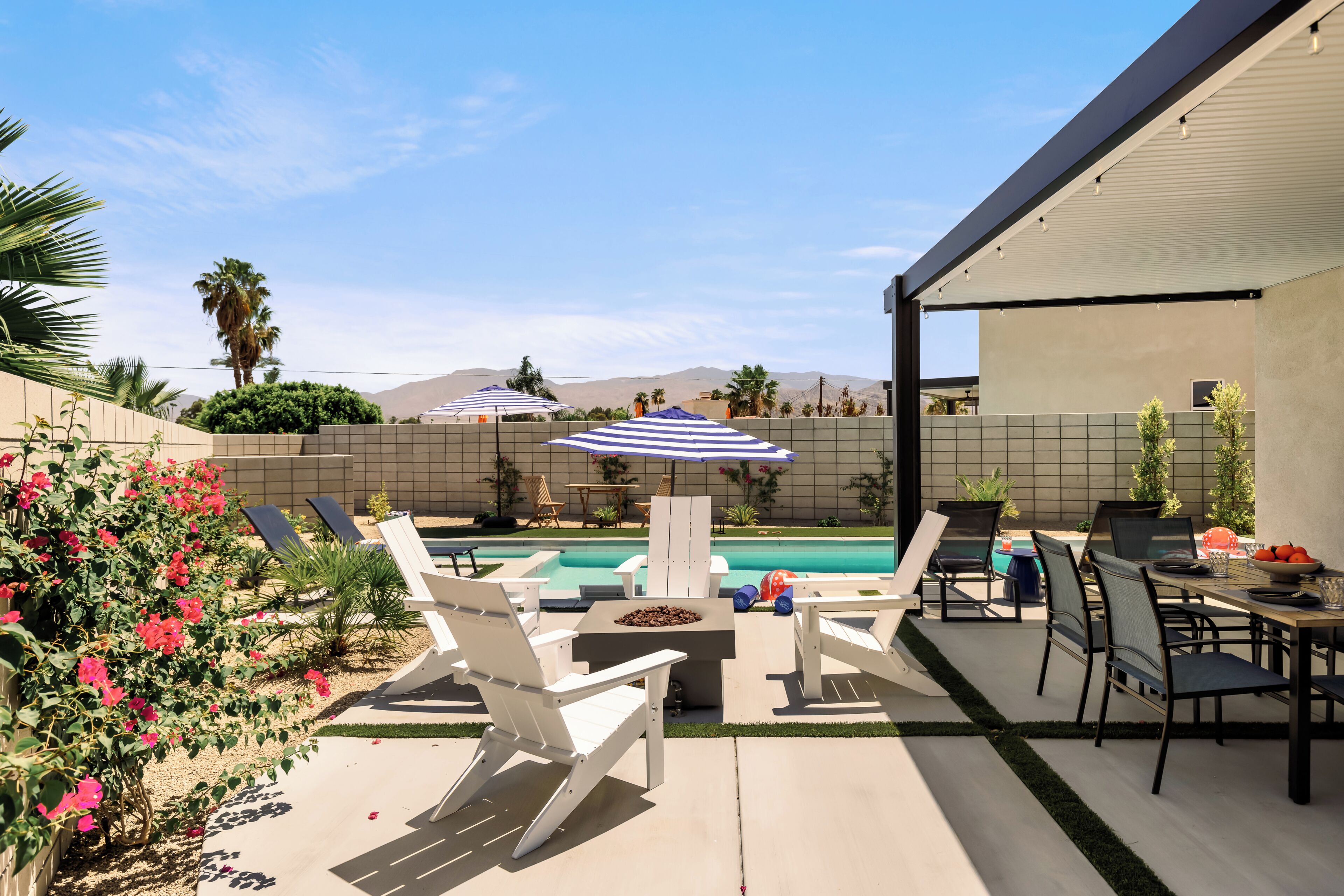 Un patio con piscina, sillas de descanso y sombrillas.