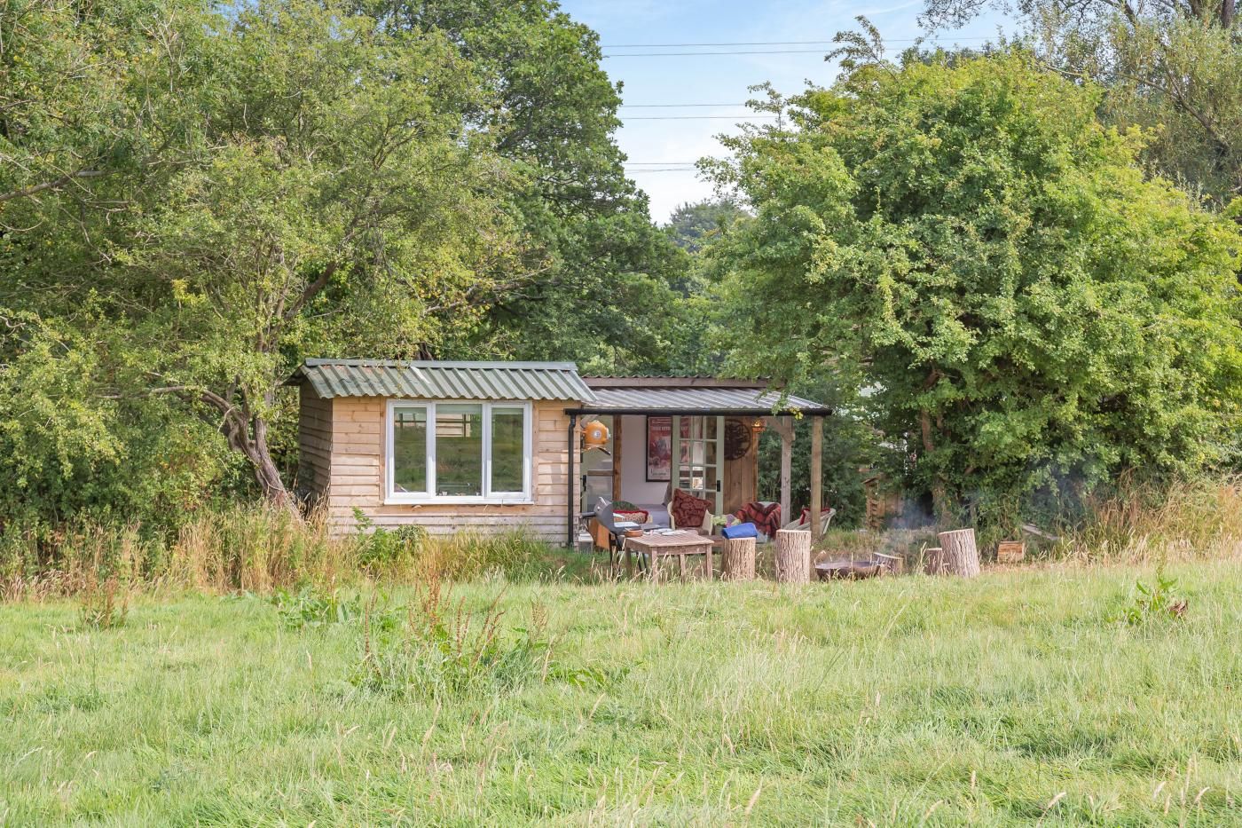 A small wooden cabin with a porch, surrounded by lush greenery.
