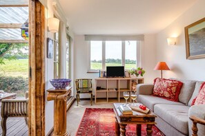 Ein gemütliches Wohnzimmer mit Sofa, Couchtisch, Fernseher und Bücherregal.
